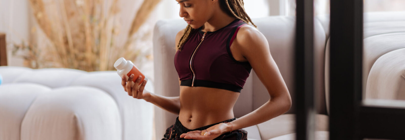 Woman Taking Care Of Body Sitting On Sofa And Taking Supplements