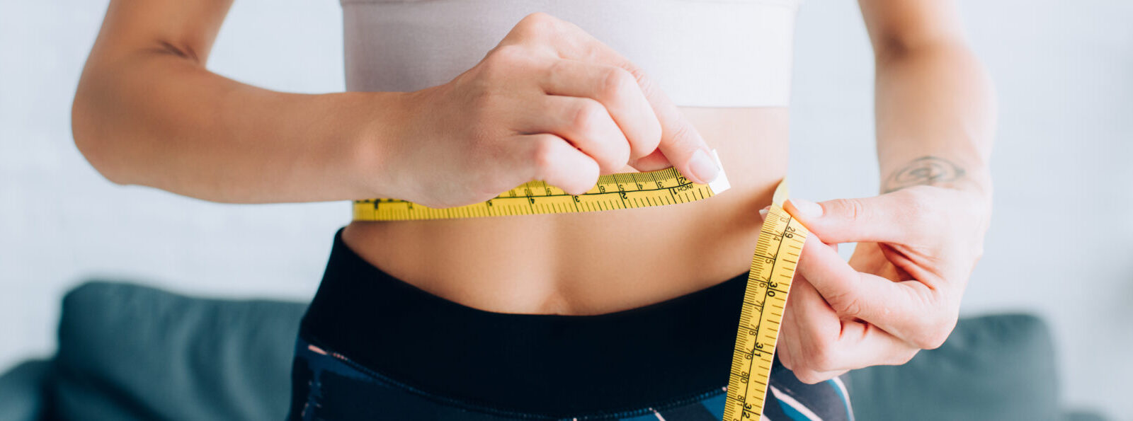 Panoramic Crop Of Fit Sportswoman Measuring Waist At Home